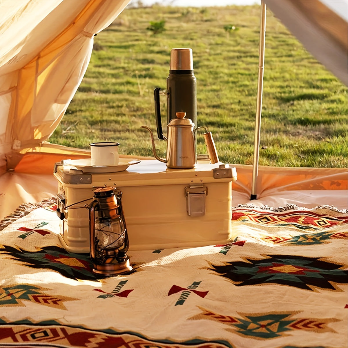 Camping scene with a thermos, kettle, and lantern on a patterned blanket inside a tent.